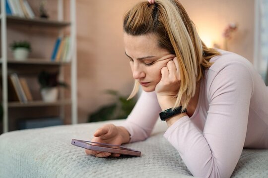 Woman feeling sad and bored doomscrolling on smartphone