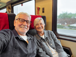 Naklejka premium Happy senior couple traveling by train enjoying a relaxing journey and retirement vacation