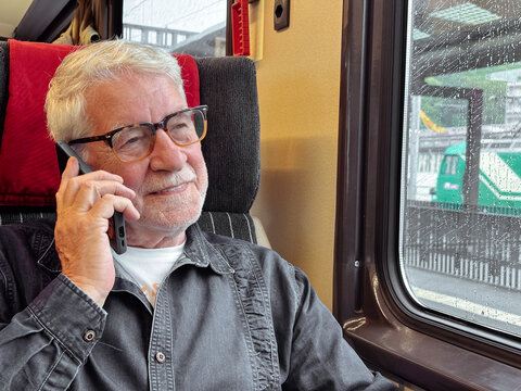 Senior man talking on mobile phone during a train journey, enjoying conversation and travel