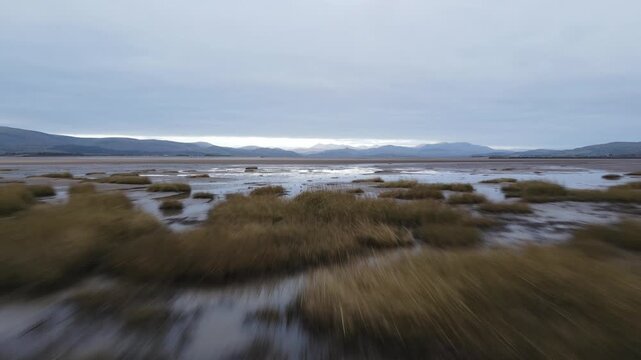 Aerial footage over quicksand towards middle of bat looking towards the Lake District