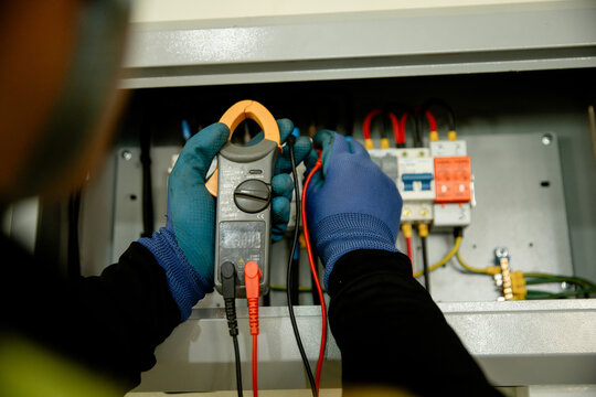 Electrical maintenance action in industrial setting technician using multimeter for safety checks