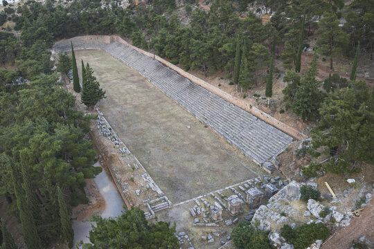 Aerial view of the Ancient Stadium of Delphi with its stone seating and long track nestled among pine trees on the hillside Delphi, Greece.