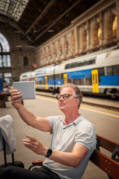 Mature businessman making video call with tablet while waiting at railway station