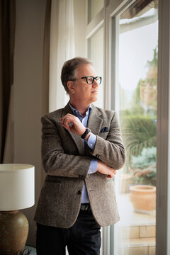 Mature businessman looking through window and reflecting on future plans