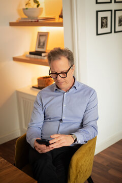 Mature man using smartphone while sitting at home