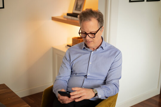 Mature man using smartphone while sitting at home