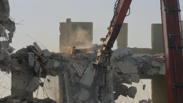 Excavator with hydraulic crusher is tearing down the old typical Turkish multi-storey apartment, residential building in Istanbul, Turkey - demolition of building