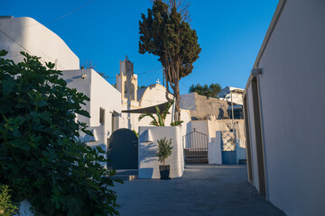 Sunny view of traditional Cycladic church buildings and quiet courtyard with blue sky on Santorini island. © Andrei Tomas