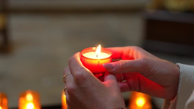 Hands holding a glowing devotional candle during Christian prayer