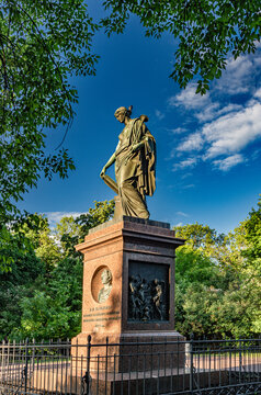  A bronze statue of the music historian Clio in antique garb against a blue sky with clouds, located in Karamzin Square in Ulyanovsk.