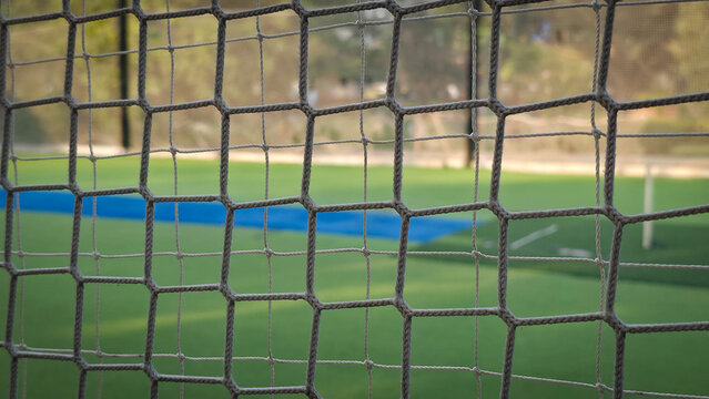Close-up of a Soccer Goal Net on a Green Field with Blurred Background