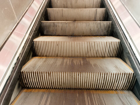 Close-up of escalator steps with brown seats