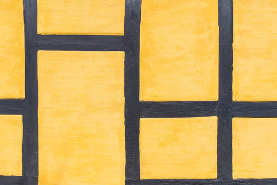Close-up of traditional Danish half-timbered architecture (bindingsv&aelig;rk) with black wooden beams and yellow plaster wall in Copenhagen, Denmark with abstract geometric pattern