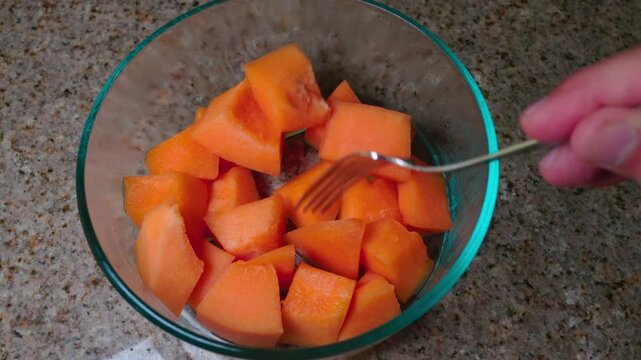 A fork picks up fresh cantaloupe pieces