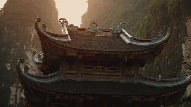 Sunset in Ninh Binh Vietnam, limestone mountains and serene waters with traditional pavilion.