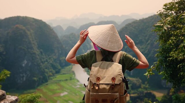 Young female tourist with backpack exploring scenic Ninh Binh mountains and waterways.
