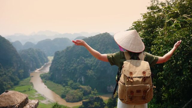 Asian young adult exploring scenic Ninh Binh Vietnam with backpack in traditional hat, concept trip travel.