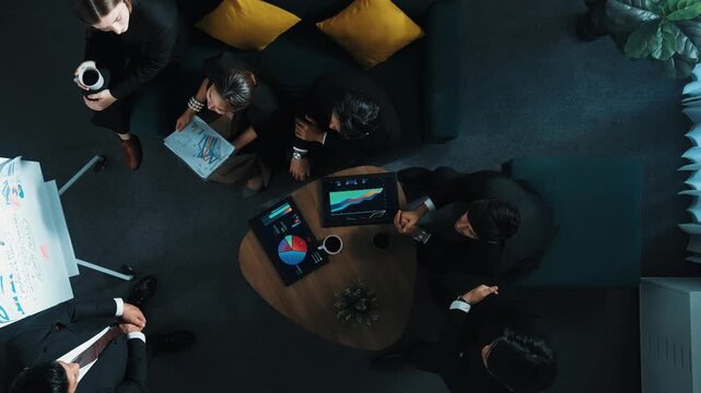 Top down view of business people listen businessman present idea while making decision. Group of diverse team making a decision to invest start up project while hold tablet display graph. Directorate.