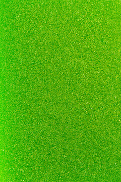 Green porous foam surface macro close up. Bright lime kitchen sponge material provides detailed textured backdrop for cleaning industry advertisement graphic resource or household product presentation
