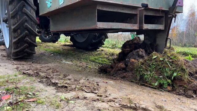 Tractor digging and moving soil with a plow in an autumn agricultural field