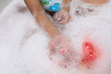 Fototapeta premium Child holding a surprise toy capsule found inside a dissolving bath bomb.