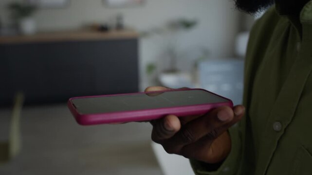 Close up of African American young adult man recording voice command for AI assistant on smartphone in office. For commercial videos about AI voice recognition, mobile apps, and modern communication