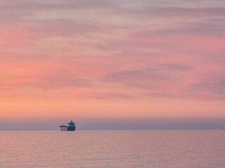 Obraz premium Ship silhouette on calm sea at sunset
