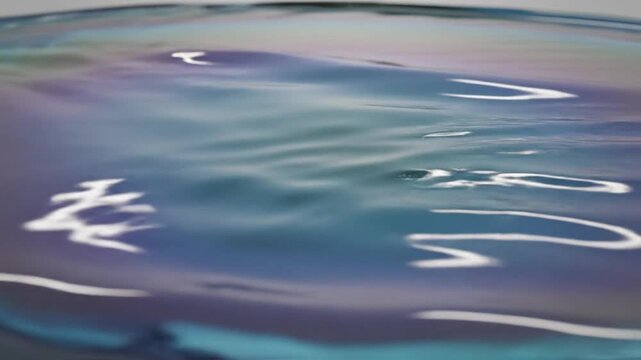 Macro shot of iridescent liquid glass surface featuring smooth ripples, pearlescent blue and purple color gradients, soft light reflections, and modern abstract aesthetic textures.
