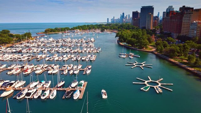 Following a boat moving to the berth in the harbor. Green trees grow at the waterfront around. Chicago, Illinois, USA.