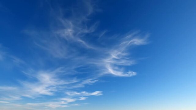 Wide angle shot of bright blue sky with thin wispy white cirrus clouds and visible lens flare from sunlight across the open atmosphere on a clear day without obstruction.