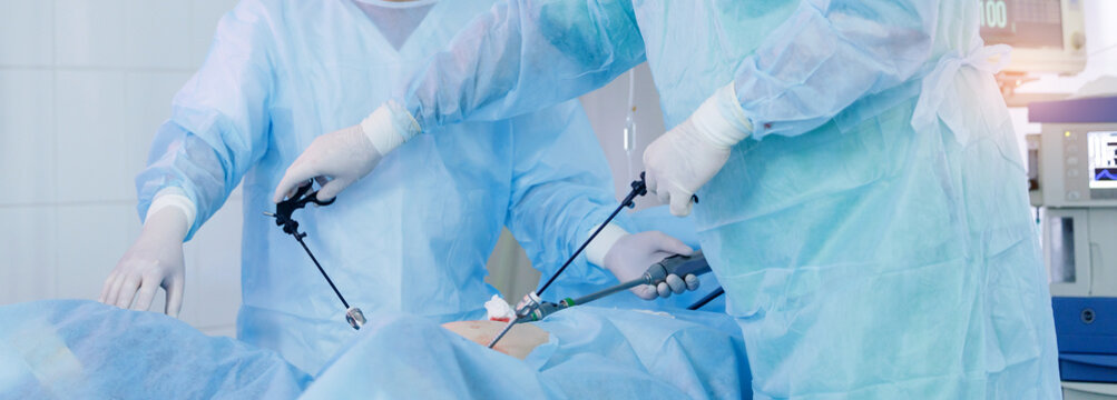 Multiple surgeons conducting minimally invasive surgery in operating room, banner