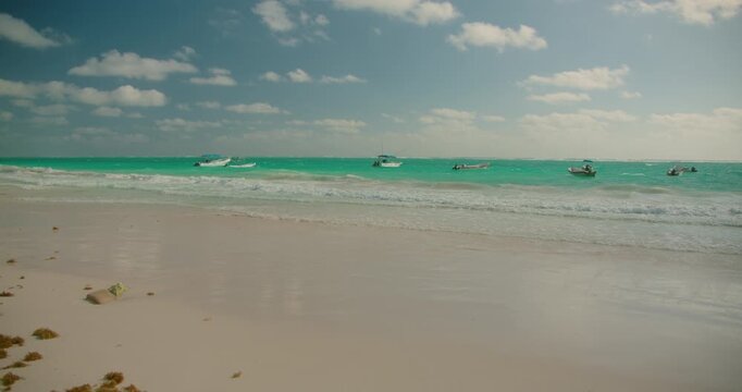 Boats float on turquoise water under cloudy sky at Playa Santa Fe Tulum Mexico