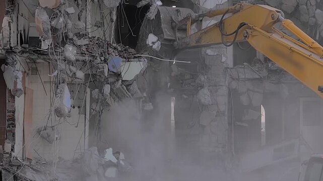 Yellow excavator with shovel bucket tearing down the old typical Turkish multi-storey apartment, residential building in Istanbul, Turkey - slow motion, demolition of building