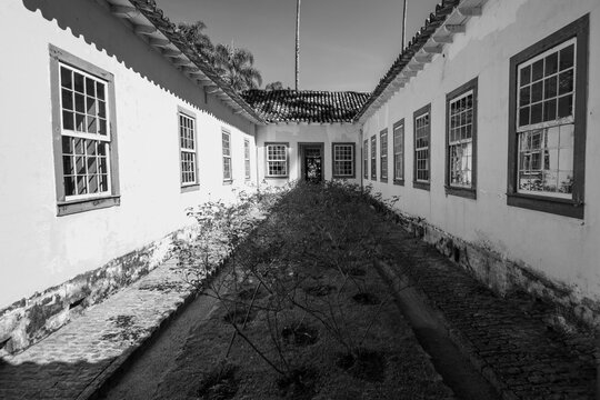 The photo shows an inner courtyard of a colonial building, likely an old house or historic farm. The space is formed by two parallel wings.