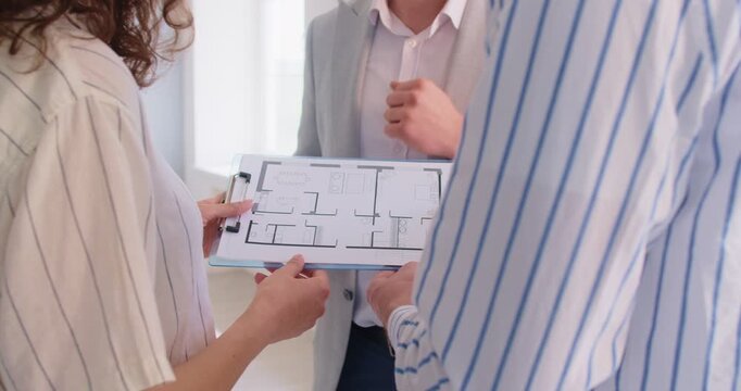 Close up realtor or architect handshaking with, presenting detailed floor plan or architectural blueprint of new property or construction project. Client agent trust, real estate consultation
