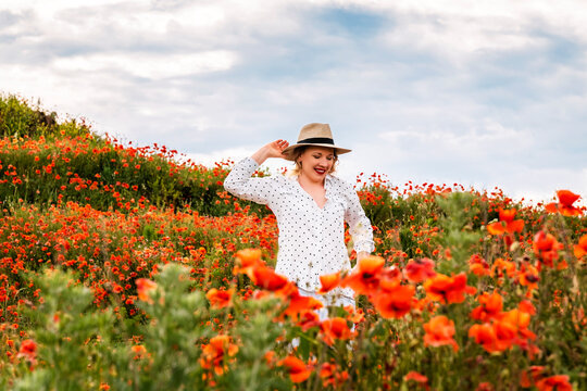 Woman poses amidst vibrant poppy field. Serene nature connection, summer atmosphere.