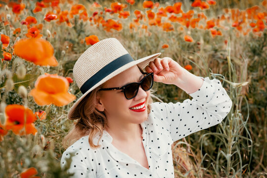 Stylish woman in hat, sunglasses among poppies. Summer chic, elegant vacation vibe.