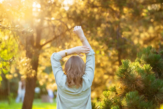 Radiant woman stretches in sun-drenched forest. Golden hour warmth, peaceful nature connection.