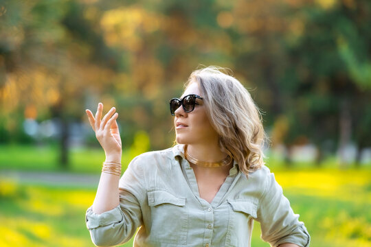 Elegant woman gazes upwards in sunny meadow. Relaxed vacation mood, serene nature escape.