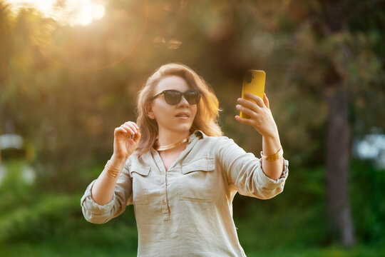 Modern woman captures memories in sunny park. Smartphone connection, lifestyle technology balance.