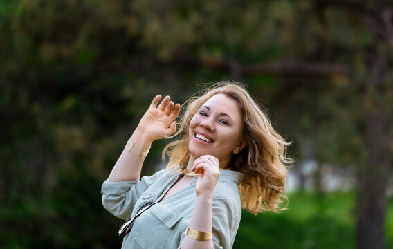 Lively woman laughs in sunlit nature. Dynamic movement, contagious summer spirit.