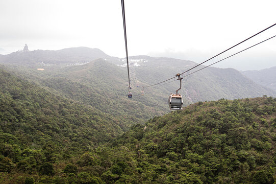 High angle view of Ngong Ping 360 cable car cabins moving over lush green mountains on Lantau Island in Hong Kong