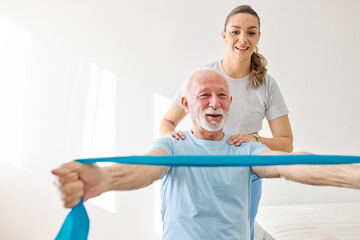 Naklejka na ściany i meble Doctor or nurse or physiotherapist caregiver exercise with senior woman at clinic or nursing home