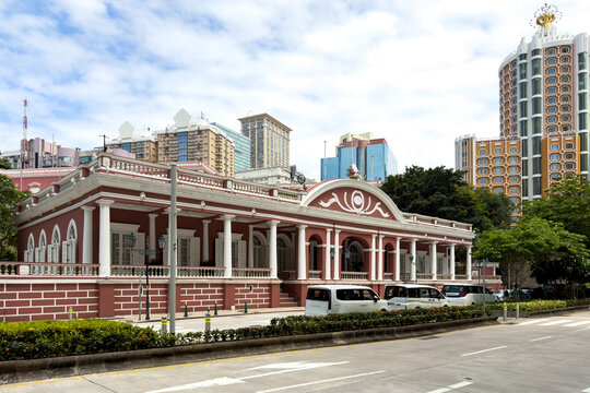 Historical Portuguese colonial building of Clube Militar de Macau contrasted with modern city high-rises in Macau