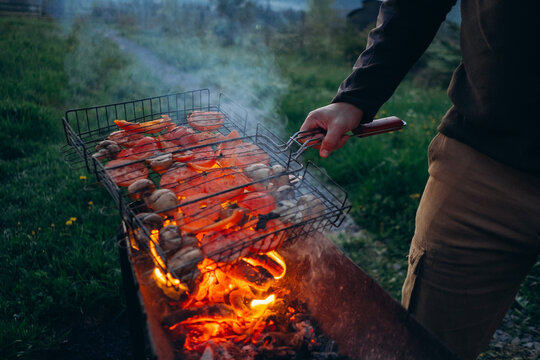 Person grilling vegetables over open fire outdoors