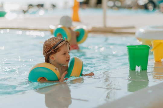 Happy toddler playing in pool during summer vacation.