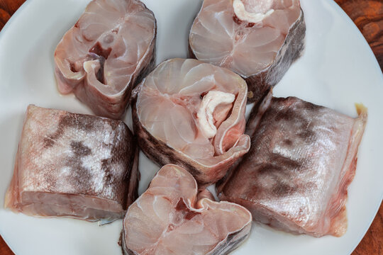 Pieces of raw kingklip on a white plate close-up