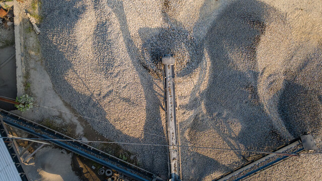 Aerial view of a conveyor belt transporting crushed stones onto large gravel piles at the Babakan industrial site in Karanglewas, Central Java, Indonesia.