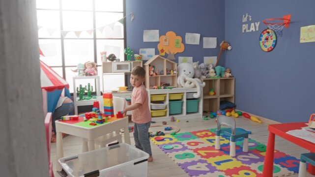 Boy stacking colorful blocks on a play table inside a children's playroom building; playful imagination.