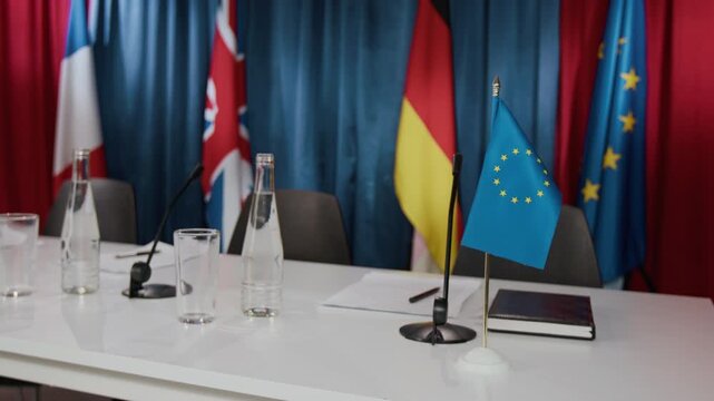 Empty international conference table with European Union flag, microphones, and water bottles standing ready for summit. Perfect for news broadcasts, political documentaries, or global reports